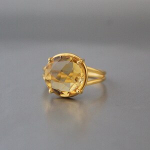 K&ouml;nnte beinhalten: Ein goldener Ring mit einem gro&szlig;en, runden, facettierten Topas-Edelstein.