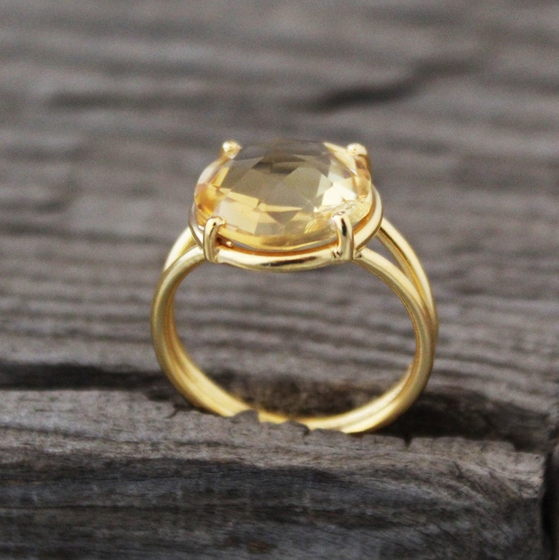 K&ouml;nnte beinhalten: Ein goldener Ring mit einem gro&szlig;en, ovalen, hellgelben Edelstein.