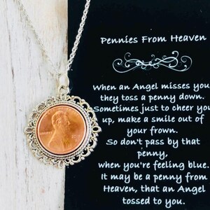 May include: A silver necklace with a copper penny pendant. The pendant is surrounded by a decorative silver frame. The necklace comes with a card that reads "Pennies From Heaven" and a poem about finding a penny.