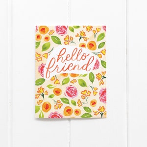 May include: A greeting card with a floral pattern of pink roses, orange flowers, and green leaves on a cream background. The words "hello friend" are written in orange script within a white speech bubble.