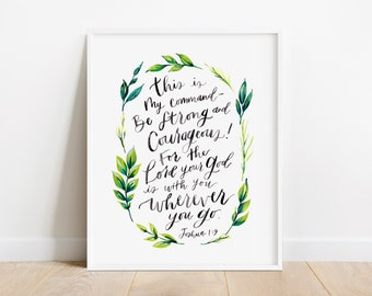 May include: A framed print with the text "This is My command - Be strong and Courageous! For the Lord your God is with you wherever you go. Joshua 1:9." The text is in black script, surrounded by a green and white watercolor leaf design.