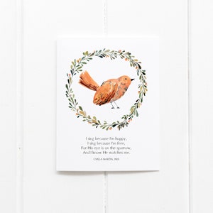 May include: A watercolor print featuring a brown bird inside a green and orange floral wreath. The print includes the text "I sing because I'm happy... CIVILLA MARTIN, 1905" on a white background.