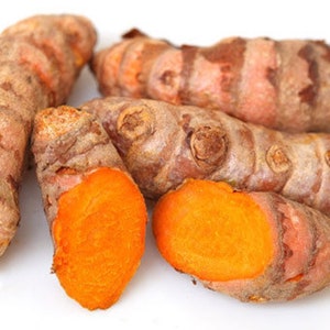 Puede incluir: Primer plano de raíz de cúrcuma, una especia de color naranja brillante que se utiliza en la cocina y con fines medicinales. Las raíces son marrones por fuera y tienen un interior naranja vibrante.