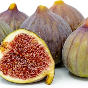 May include: A group of six ripe figs, some whole and one cut in half, revealing the red interior with small seeds. The figs are a deep purple color with a green hue and have a textured skin.