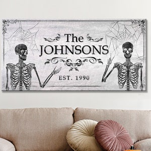 May include: A black and white Halloween-themed family name sign with two skeletons, a spiderweb design, and the text "The Johnsons Est. 1990".