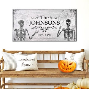 May include: A black and white Halloween-themed sign with two skeletons, a spiderweb, and the text "The JOHNSONS EST. 1990".