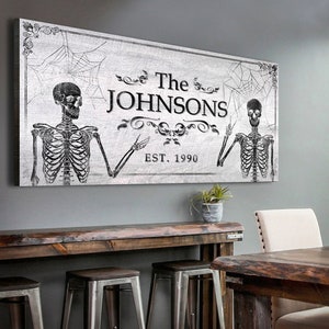 May include: A black and white Halloween-themed family name sign with two skeletons, a spiderweb, and the text "The Johnsons Est. 1990".