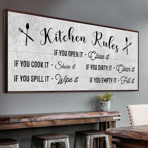 A Farmhouse Kitchen canvas sign with Kitchen rules on it on a distressed white wooden-inspired background.