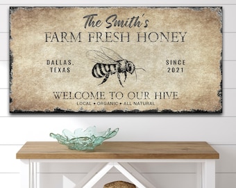 Puede incluir: Un letrero de madera rústico con el texto "The Smith's Farm Fresh Honey" y una ilustración de abeja. El letrero también incluye el texto "Dallas, Texas", "Since 2021", y "Welcome to Our Hive Local Organic All Natural".