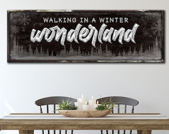 May include: A rectangular wooden sign with the words "WALKING IN A WINTER WONDERLAND" in white script. The sign has a dark background with a snowy forest scene and snowflake accents. The sign is above a wooden table with chairs.