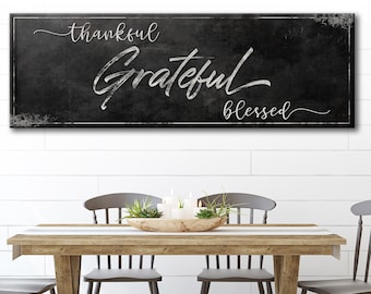 May include: Black and white sign with the words "thankful, grateful, blessed" written in a cursive font on a distressed background.