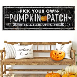 May include: A black and white sign with distressed lettering that reads "Pick Your Own. Pumpkin Patch" with a pumpkin graphic and the text "Est. 25¢ per pound - 100% Organic 2021".