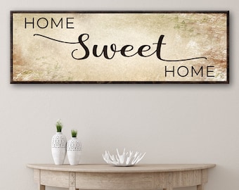 May include: A rustic wooden sign with a distressed beige background and black lettering. The sign reads "Home Sweet Home".