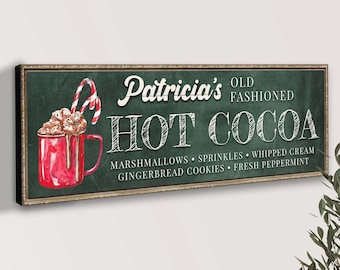 May include: A green chalkboard sign with white lettering that reads "Patricia's Old Fashioned Hot Cocoa" with a red mug of hot cocoa with marshmallows and a candy cane on top. The sign also lists the ingredients: marshmallows, sprinkles, whipped cream, gingerbread cookies, and fresh peppermint.