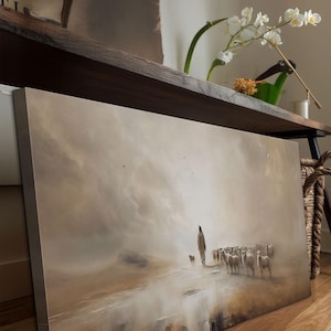 Puede incluir: Una impresi&oacute;n art&iacute;stica en lienzo representa a un pastor y un reba&ntilde;o de ovejas en un paisaje sepia. La obra presenta una figura solitaria guiando a las ovejas a trav&eacute;s de una escena brumosa, evocando tranquilidad y vida pastoral.