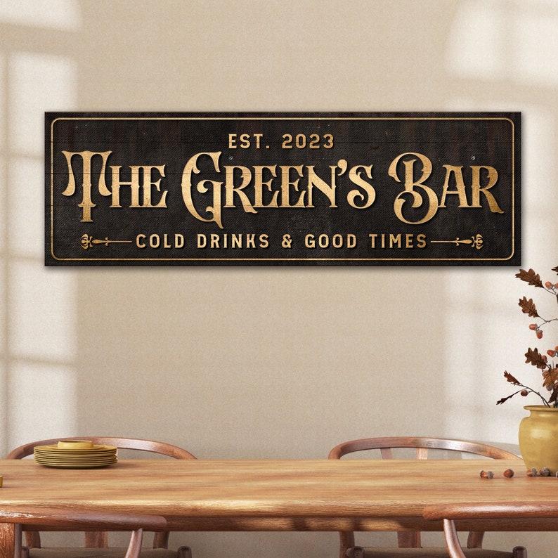 K&ouml;nnte beinhalten: Ein schwarzes Holzschild mit goldenen Buchstaben, auf dem "The Green's Bar Est. 2023 Cold Drinks & Good Times" steht.