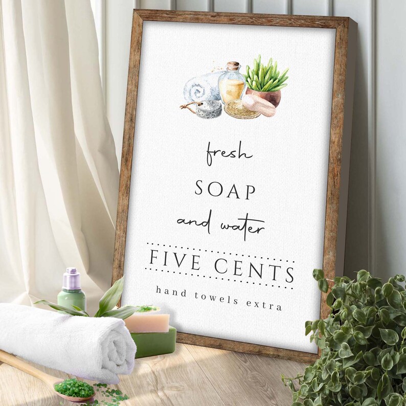 May include: A white sign with a wooden frame, featuring a watercolor illustration of soap, water, and a towel. The sign reads "fresh soap and water FIVE CENTS hand towels extra".