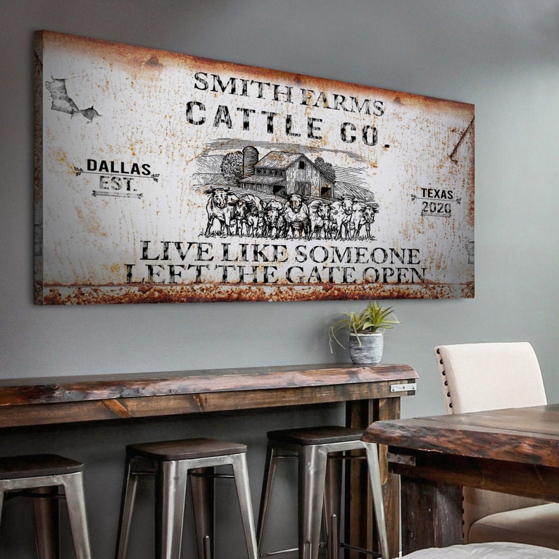 May include: A rustic metal sign with the text "Smith Farms Cattle Co." and the dates "Dallas Est." and "Texas 2020". The sign also features a black and white illustration of a farm scene with a barn and cattle. The text "Live like someone left the gate open" is printed below the illustration.