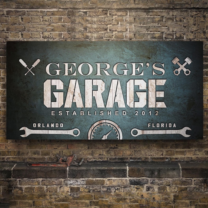 May include: A distressed-look sign with the text "GEORGE'S GARAGE ESTABLISHED 2012" in white lettering. The sign includes images of tools and the locations Orlando and Florida. The background is a teal color.