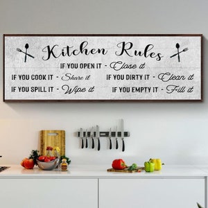 A Farmhouse Kitchen canvas sign with Kitchen rules on it on a distressed white wooden-inspired background.