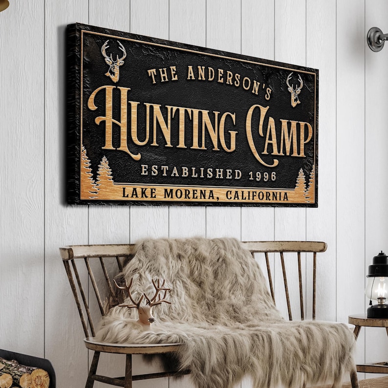 May include: Black and gold sign with the text "The Anderson's Hunting Camp Established 1996 Lake Morena, California" with a deer silhouette on each side.