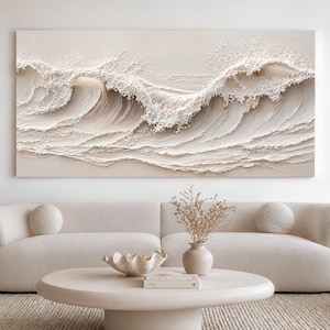May include: A large rectangular wall art piece featuring a textured, monochromatic cream-colored relief of crashing ocean waves. The artwork displays thick, sculpted layers of paint that mimic the movement and foam of breaking sea waves.