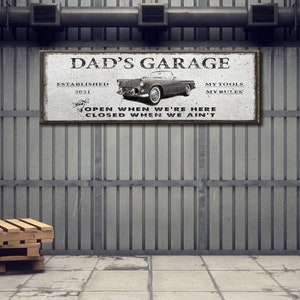 Puede incluir: Un letrero en blanco y negro con el texto "Dad's Garage" y "Establecido en 2021". El letrero tambi&eacute;n presenta un autom&oacute;vil antiguo y el texto "Mis herramientas, mis reglas" y "Abierto cuando estamos aqu&iacute;, cerrado cuando no estamos".
