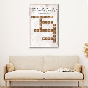 May include: A white canvas print with a brown marble background. The print features a scrabble tile word art design with the names "Jonathan", "Emily", "Benjamin", and "Jose" spelled out in brown tiles. The text "The Smiths Family Established 2018" is at the top of the print.