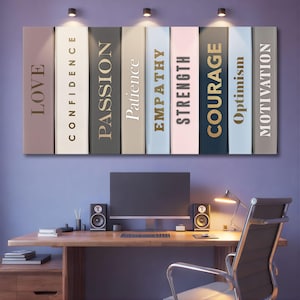 May include: A motivational wall art piece featuring a series of book spines with words like "LOVE", "CONFIDENCE", and "PASSION" in gold lettering. The artwork hangs above a wooden desk with a computer monitor, speakers, and a desk lamp.