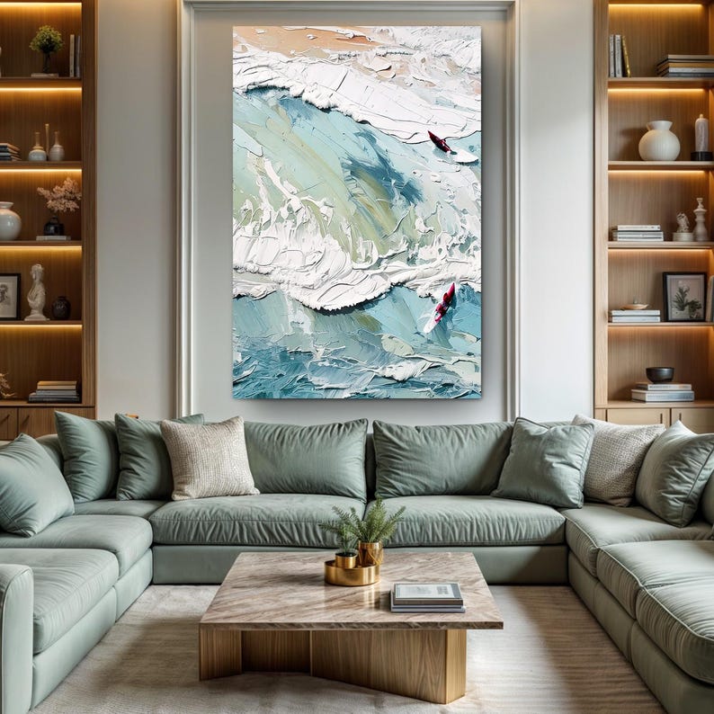 May include: Large abstract oil painting of ocean waves in shades of blue, white, and beige. Two figures on surfboards are visible. The artwork is displayed above a green sectional sofa in a living room.