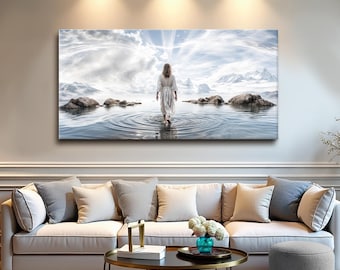 May include: A large rectangular canvas print depicts a person walking in water towards a bright light. The scene includes mountains, rocks, and a cloudy sky. The artwork is displayed above a beige sofa with gray pillows.