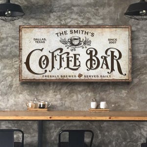 Może przedstawiać: W stylu vintage znak dla kawiarni o nazwie "The Smith's Coffee Bar". Znak jest biały z brązowymi literami i przedstawia filiżankę kawy i ziarna kawy. Znak zawiera r&oacute;wnież tekst "Dallas, Texas" i "Since 2007". Na dole znaku widnieje napis "Freshly Brewed Served Daily".
