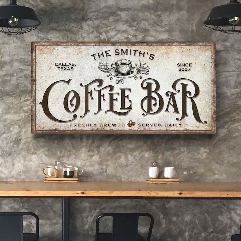 Może przedstawiać: W stylu vintage znak dla kawiarni o nazwie "The Smith's Coffee Bar". Znak jest biały z brązowymi literami i przedstawia filiżankę kawy i ziarna kawy. Znak zawiera r&oacute;wnież tekst "Dallas, Texas" i "Since 2007". Na dole znaku widnieje napis "Freshly Brewed Served Daily".