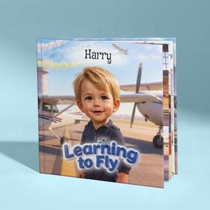 Könnte beinhalten: Ein Kinderbuch mit dem Titel "Learning to Fly" mit einem lächelnden Kind in einer Pilotenuniform. Das Cover zeigt das Kind vor einem Flugzeug, mit dem Namen "Harry" darüber. Das Buch hat ein blaues und weißes Farbschema.