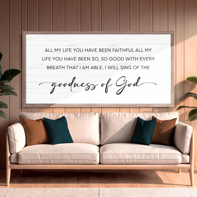 Puede incluir: Una obra de arte enmarcada con el texto "ALL MY LIFE YOU HAVE BEEN FAITHFUL... goodness of God" en escritura negra. La obra de arte cuelga sobre un sof&aacute; beige con cojines decorativos marrones y verde azulado.