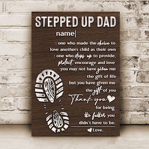 May include: A brown wooden sign with white text that reads "Stepped Up Dad" and a personalized name. The sign also includes a quote about the love and support of a stepdad. The quote includes the words "protect, encourage, and love".