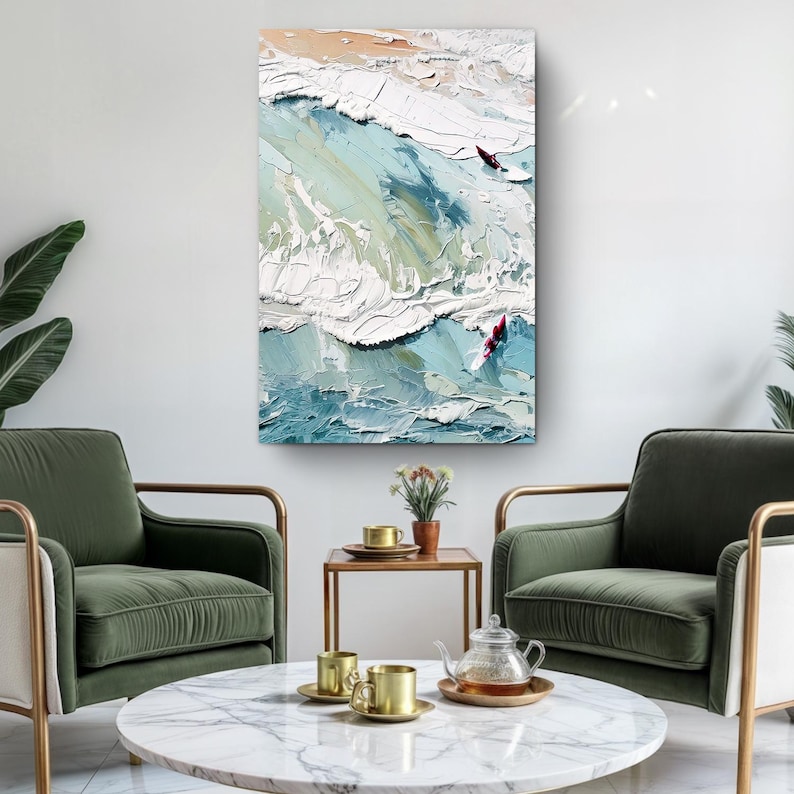 May include: Abstract ocean wave painting with textured brushstrokes in shades of blue, white, and beige. Two red figures are visible on the waves. The artwork is displayed on a white wall, above two green armchairs.