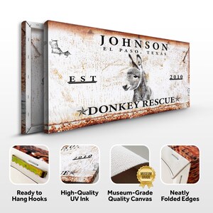 May include: A white canvas print with a rustic, distressed look. It features a donkey's head with the text "JOHNSON EL PASO, TEXAS EST 2010 DONKEY RESCUE" in black lettering. The print has a distressed, rusty look and is framed with a wooden frame.