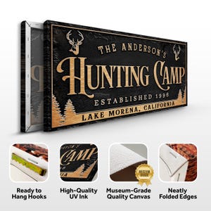 May include: A black and brown wooden sign with the text "The Anderson's Hunting Camp Established 1996 Lake Morena, California". The sign features a deer silhouette and a stylized font.