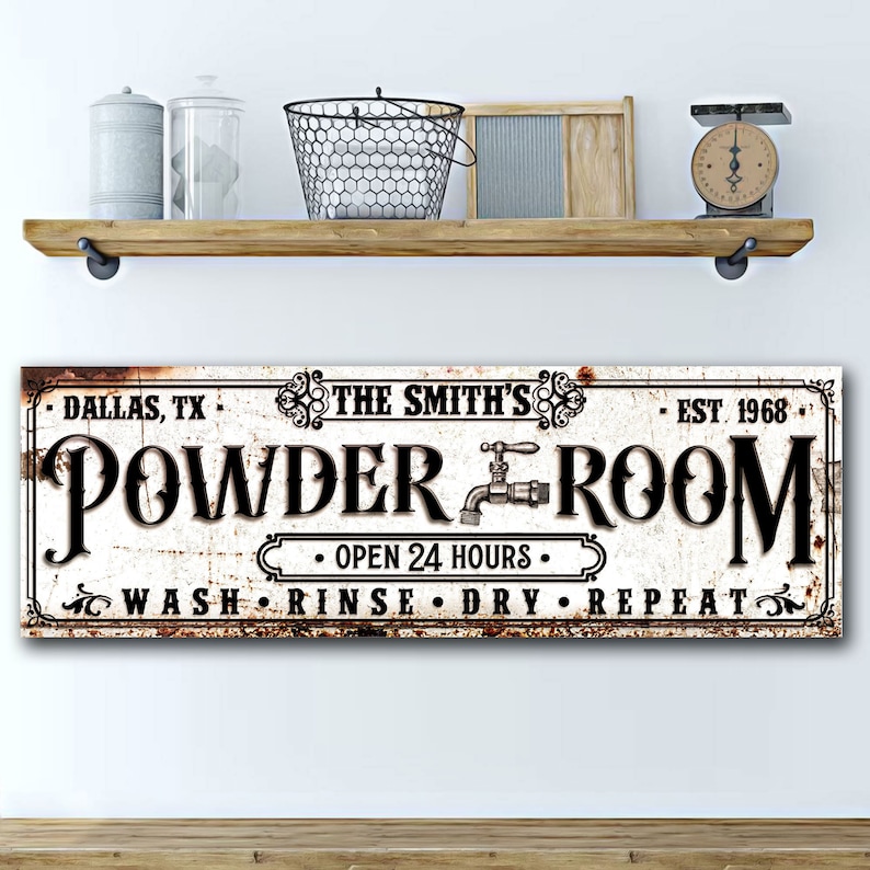 May include: A white sign with black text and a rusty brown border. The sign reads "DALLAS, TX THE SMITH'S EST 1968 POWDER ROOM &bull; OPEN 24 HOURS &bull; WASH RINSE DRY REPEAT".