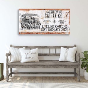 May include: A rustic metal sign with a white background and brown text. The sign reads "Smith Farms Cattle Co. Dallas Est. Texas 2020 Live Like Someone Left The Gate Open". The sign features a black and white illustration of a farmhouse and cattle.