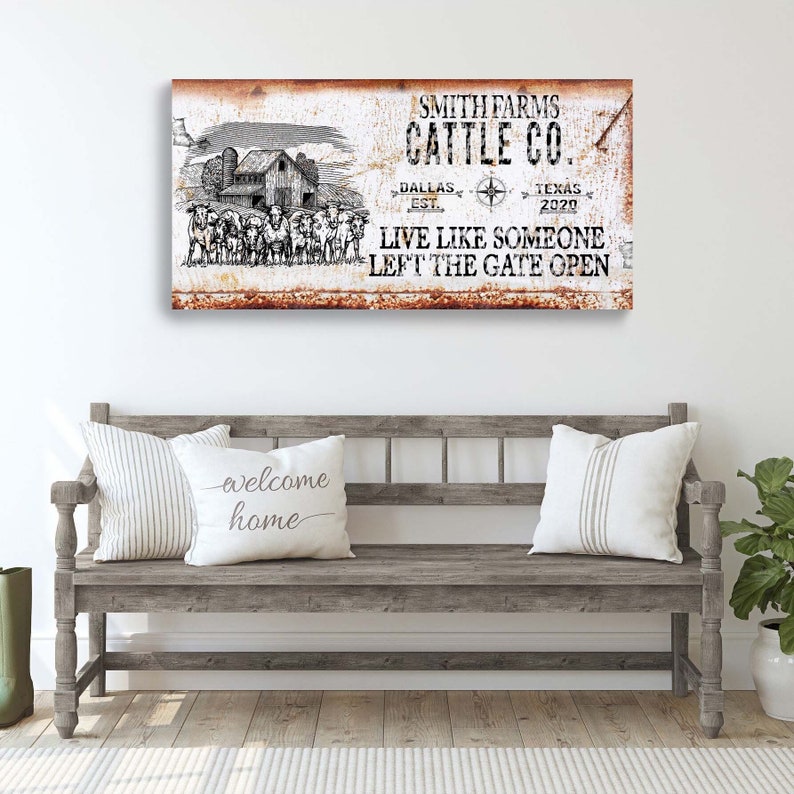 May include: A rustic metal sign with a white background and brown text. The sign reads "Smith Farms Cattle Co. Dallas Est. Texas 2020 Live Like Someone Left The Gate Open". The sign features a black and white illustration of a farmhouse and cattle.