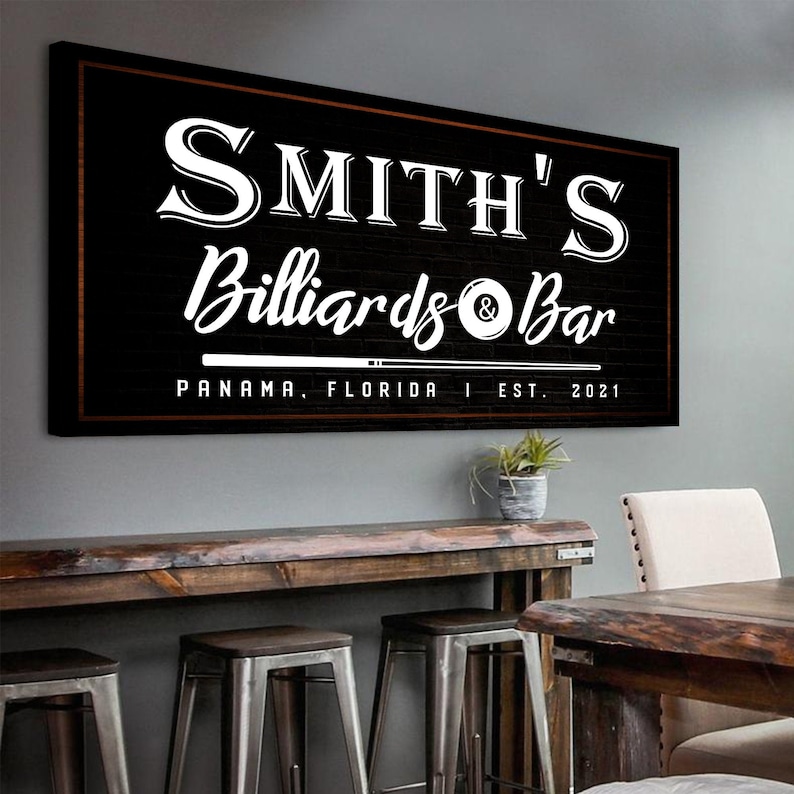 Billiard and Basement Bar sign of personalized name and established date labels with classic white cue stick and ball icons on a rustic black canvas wall décor.