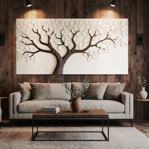 May include: A large, rectangular wall art piece featuring a textured tree design with brown branches and white leaves. The artwork hangs above a light gray sofa with matching pillows. A wooden coffee table and a vase with greenery complete the living room setting.
