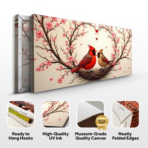 May include: Canvas wall art featuring a pair of red cardinals perched in a nest surrounded by pink cherry blossoms. The birds are looking at each other and there are small red hearts in the background. The canvas has a white border and is ready to hang with hooks.
