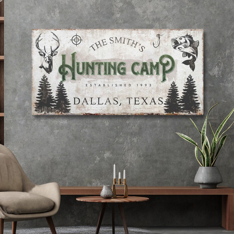 Puede incluir: Se&ntilde;al de madera r&uacute;stica con fondo blanco y texto verde que dice "The Smith's Hunting Camp Established 1993 Dallas, Texas". La se&ntilde;al presenta una cabeza de ciervo, un anzuelo y un pez.