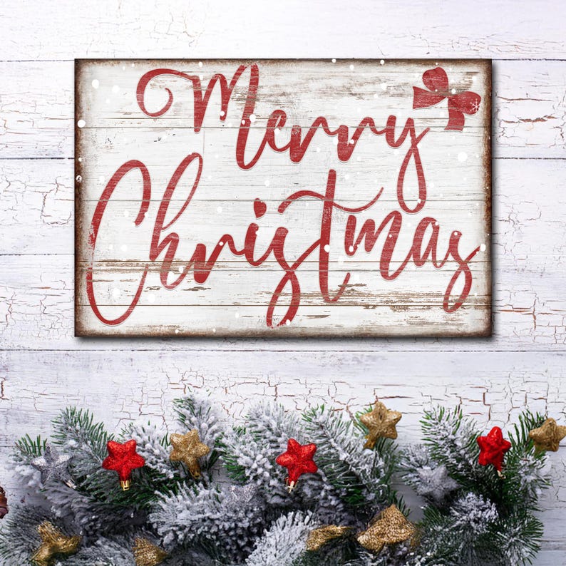 Puede incluir: Un letrero de madera blanco con letras rojas que dice "Merry Christmas" con un lazo rojo en la esquina superior derecha. El letrero est&aacute; decorado con copos de nieve blancos.