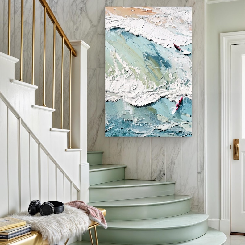 May include: An abstract oil painting of ocean waves with two surfers. The artwork features textured brushstrokes in shades of blue, white, and beige, creating a dynamic and energetic coastal scene. The painting is displayed on a marble wall.