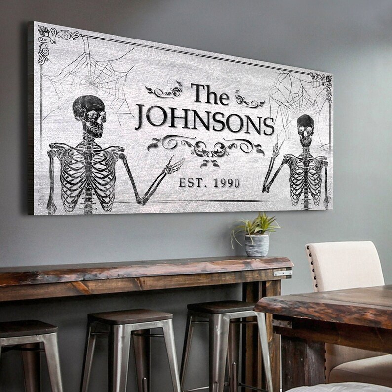 May include: A black and white Halloween-themed family name sign with two skeletons, a spiderweb, and the text "The Johnsons Est. 1990".