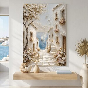 May include: A textured wall art painting depicting a coastal Mediterranean scene with white buildings, a stone path, and blooming flowers. A sailboat floats on the blue sea in the distance, while white birds fly in the sky above the bright, sunlit architecture.